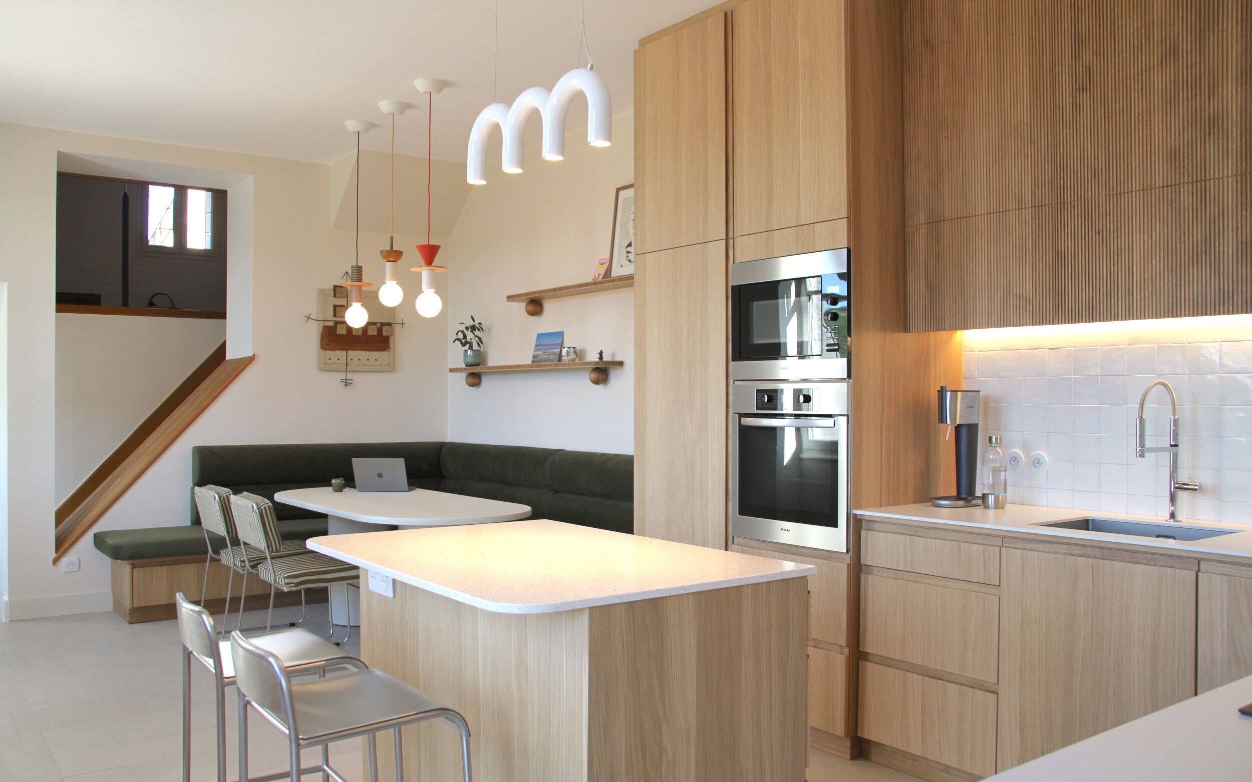 Cuisine en bois clair avec îlot et escalier en arrière-plan, maison rénovée en Côte-d’Or